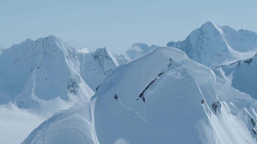 A person climbing the snow covered slopes of a mountain to reach the summit