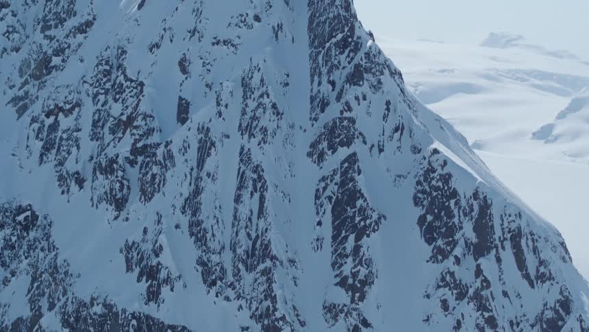 Aerial of a steep snowcovered mountain on a sunny winter day