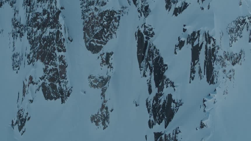 Aerial view of two people snow skiing down a snowy mountain