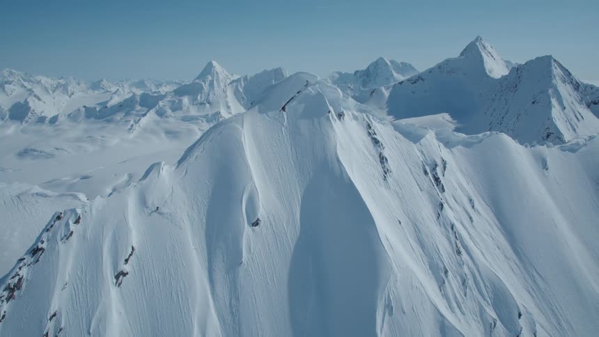 Skier skis down a steep mountain slope on a sunny winter day