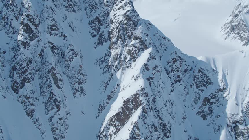 A lone skier is making their way down the steep snowcovered slope leaving faint tracks on the mountainside
