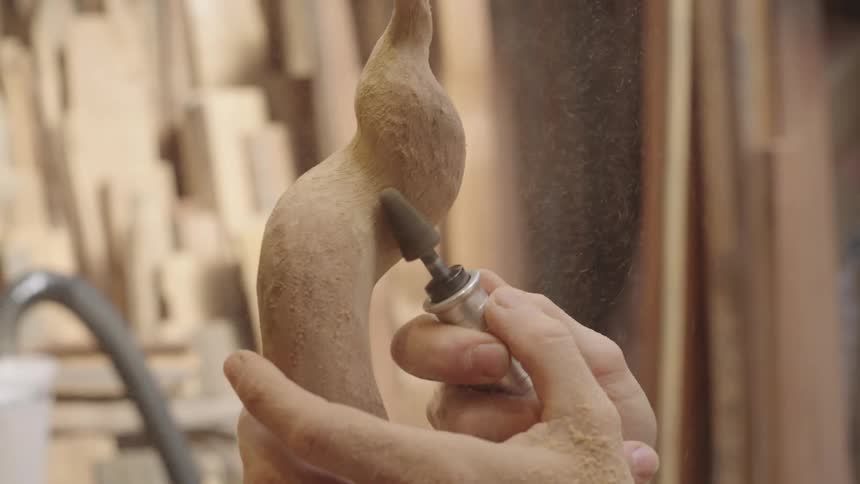 Hand of a carpenter with a tool shaping an object