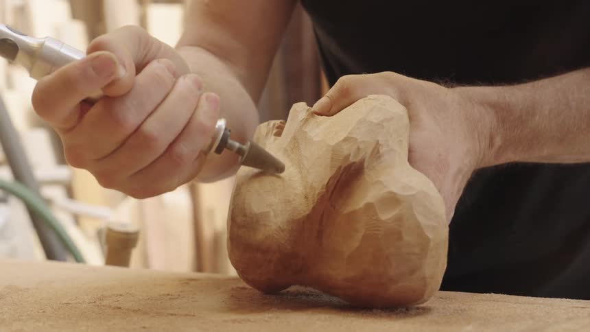 Hands of a person carving wood with a carving tool