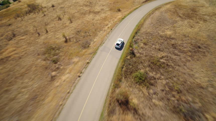 White sports car traveling along a road by a lake