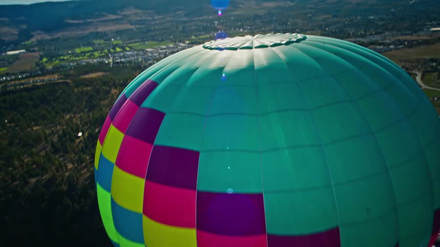 Colorful balloon flying over an urban city with mountains in the background
