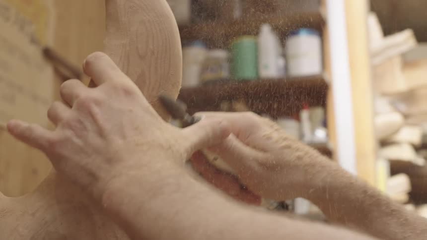 Close up of the hands of a sculptor carving a piece of wood with a power tool