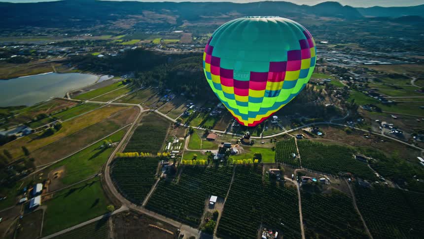 Hot air balloon floats above a rural town on a cloudy summer day