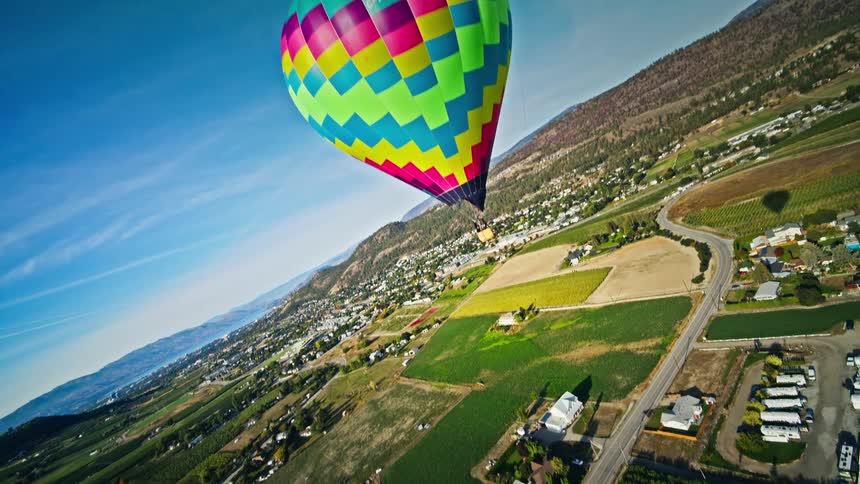 Aerial of a colorful hot air balloon flying over agricultural land in the country