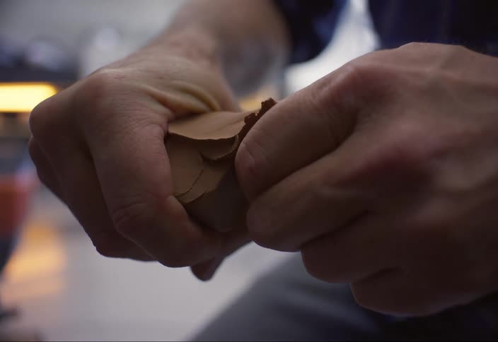 Close up of a sculptor breaking a piece of clay in half