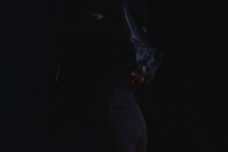 Woman next to a campfire in a black leather jacket at night