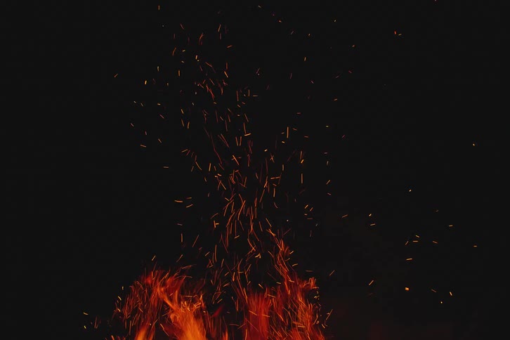 Bonfire emitting bright orange sparks at night