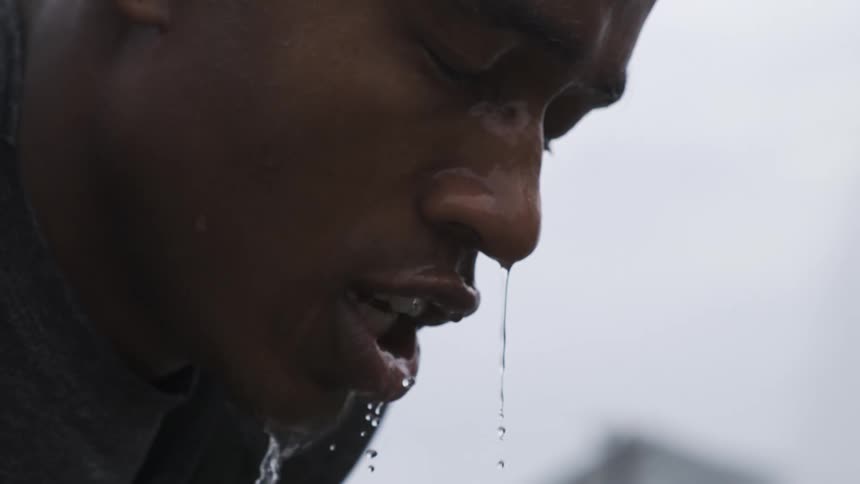 A close up of the face of a young person splashed with water