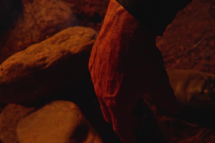 Close up of a mans hands and wrist in an outdoor setting at night