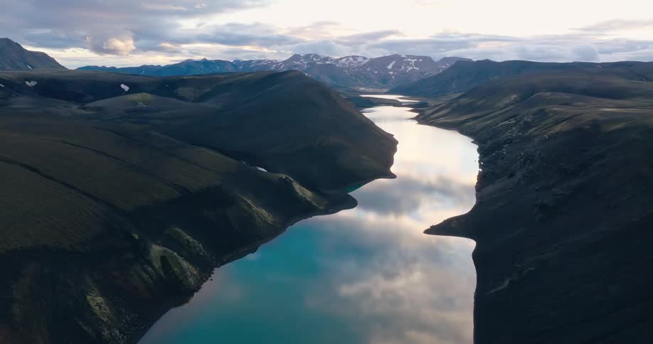 Aerial view of a lake reflecting the sky and surrounded by a mountain valley