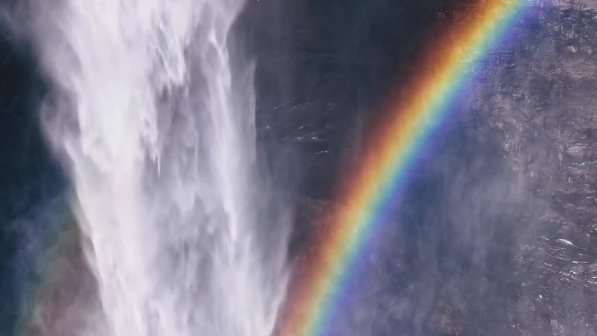 Aerial view of water falling freely over a waterfall and a rainbow