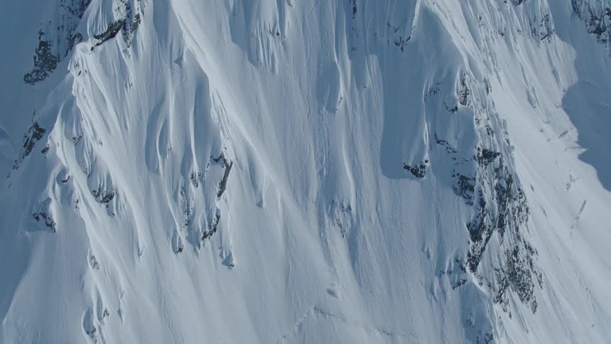 Aerial view of a person skiing in the distance on a snowy mountain