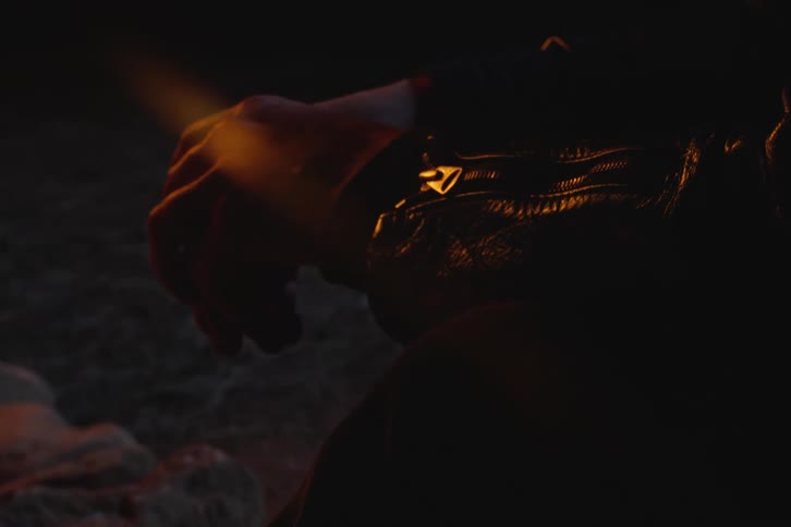 Close up of hands of a person sitting in a natural setting on rocks and wearing a black leather jacket