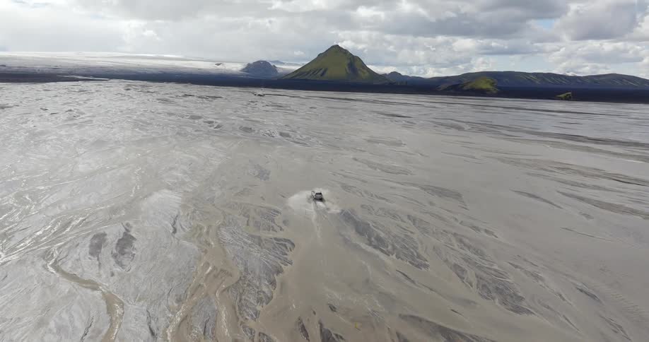 Car traveling through wet lands with a mountain valley in the background
