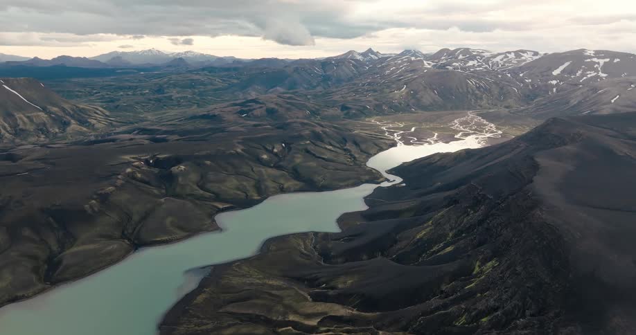 Aerial of a river running through a mountain range on a cloudy day