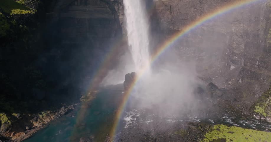 Waterfall with a rainbow visible in the mist created by the falling water