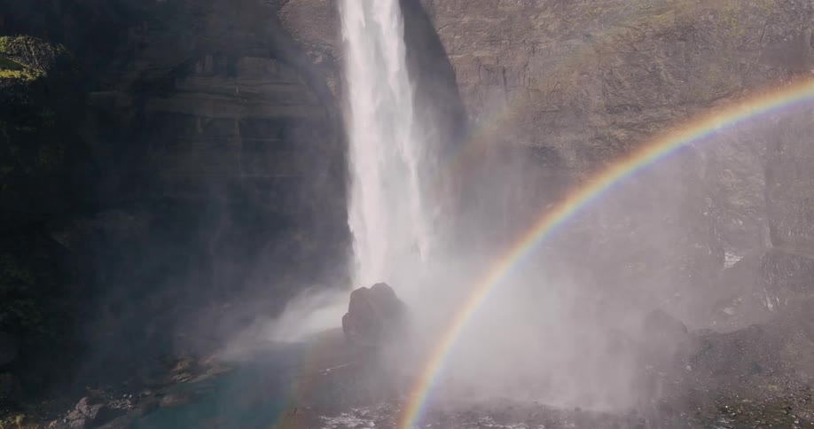 Aerial view of a waterfall falling into a valley and a rainbow