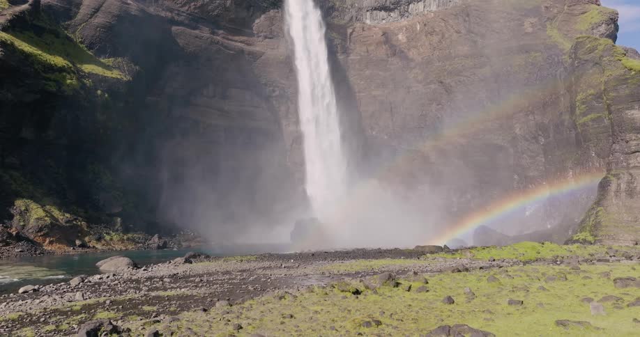 Waterfall cascading into stream below forming a double rainbow