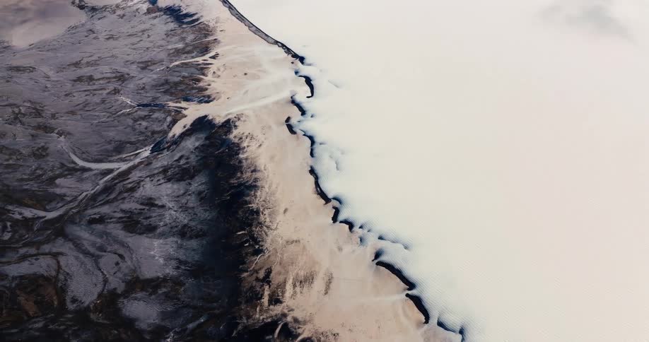 Aerial view of a coast where the land meets the sea with distinct textures and colors