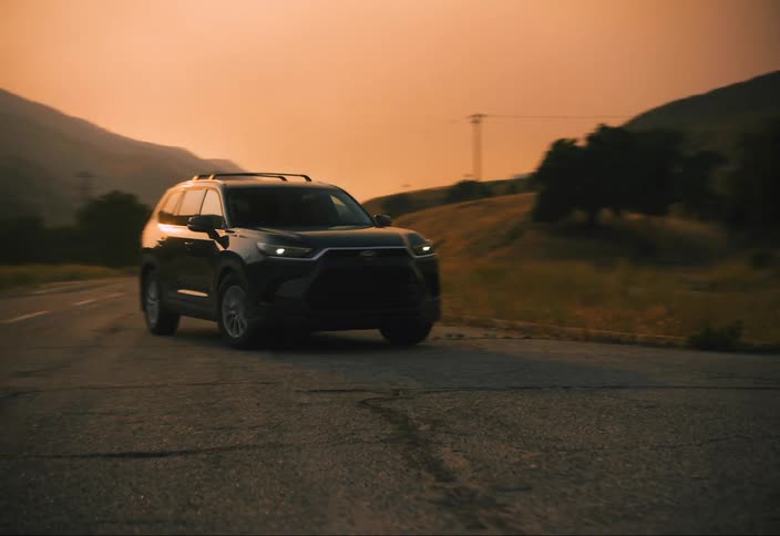 SUV makes a left turn onto a country road under orange sky