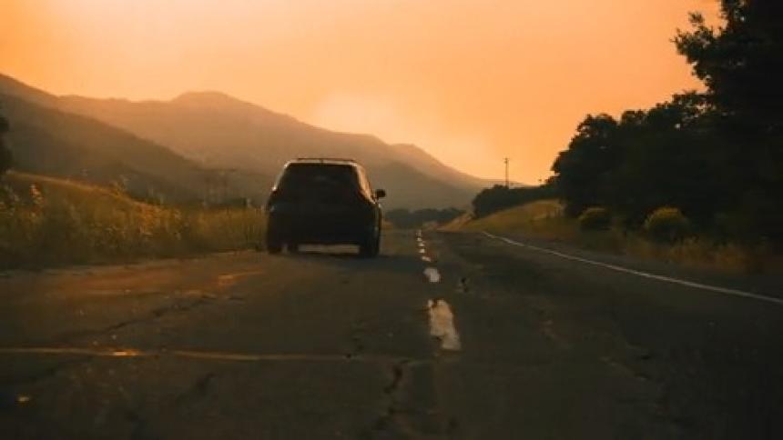 An SUV makes a left turn onto a country road and drives into the distance