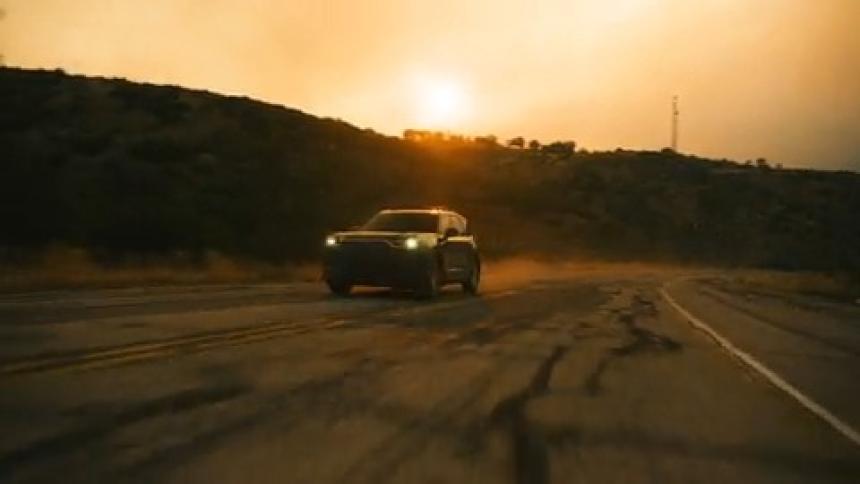 Car passes by on country road at sunset