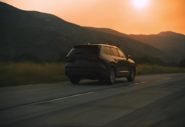 Black car driving down road away from smoky mountains