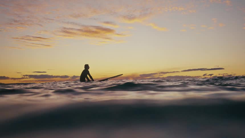 A man is floating on his surfboard in the ocean