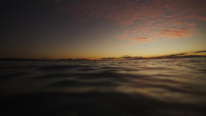 The last rays of a fiery sunset paint the sky in hues of orange and pink casting a warm glow on the calm reflective waters