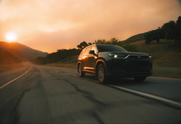 A black SUV changes lanes and drives away from a wildfire in the mountains