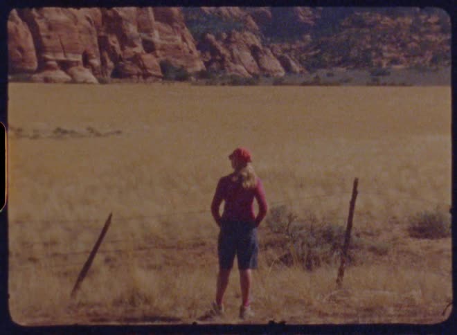View of a woman from behind looking at a landscape with canyons in the background