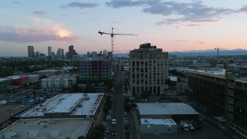 Aerial view of a city skyline at sunset with construction cranes scattered throughout