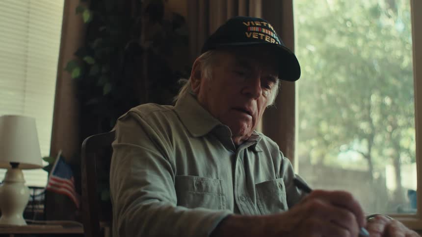 Elderly man sitting writing and thoughtful