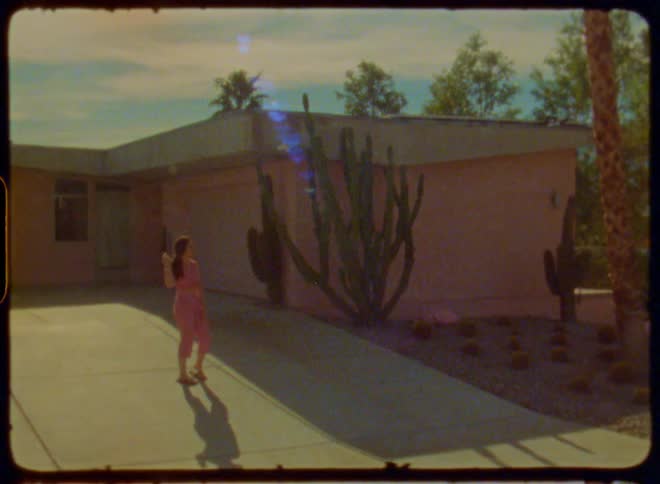 Woman in pink clothes stands in front of pink house