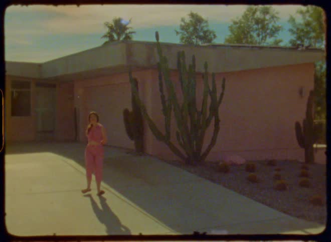 Woman in a pink outfit next to a house