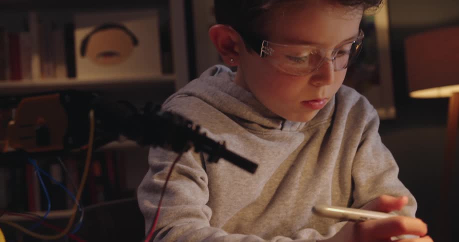 A boy working on a robotic arm in the living room at home