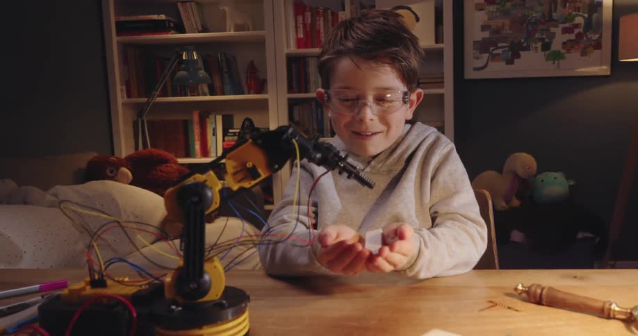 Happy boy who had a robotic hand on the table and dumped an object into his hands