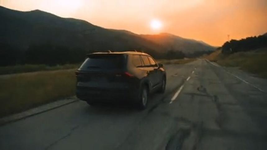 Vehicle driving on a highway with mountains in the background during sunset