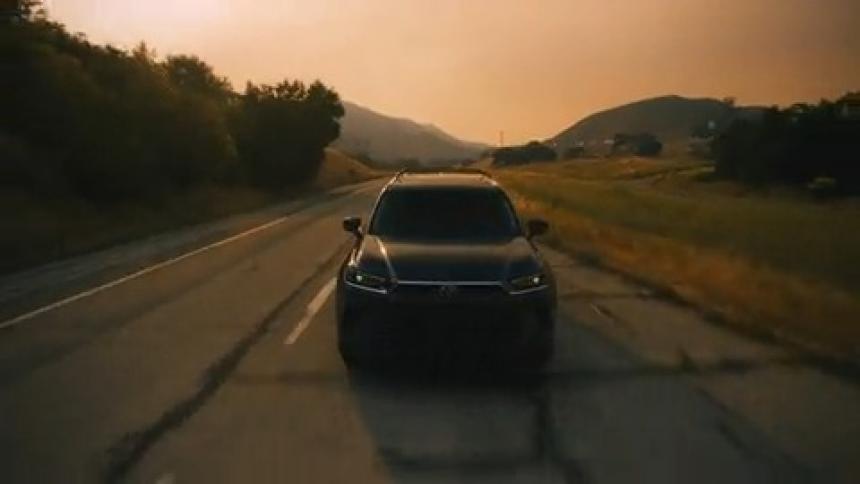 Car driving on a two lane road through a rural landscape with hills in the background