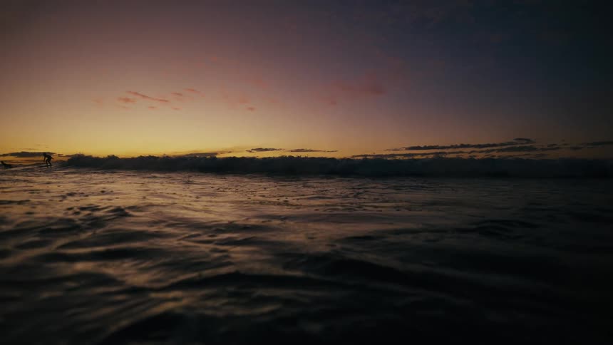 Seascape at dawn with a surfer riding a wave