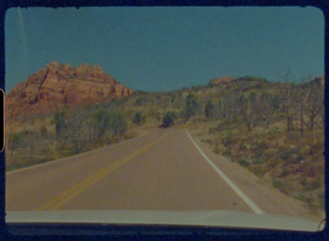 A vehicle is driving on a road around the mountain