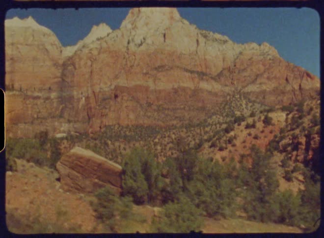 Mountainous landscape with rock formations and sparse vegetation under a clear sky