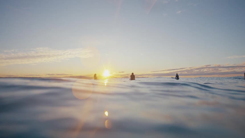 Silhouette of surfers in the ocean with the sun in the background