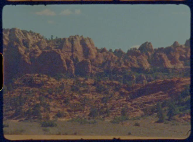 A vast arid landscape with rocky hills in the distance captured on vintage film