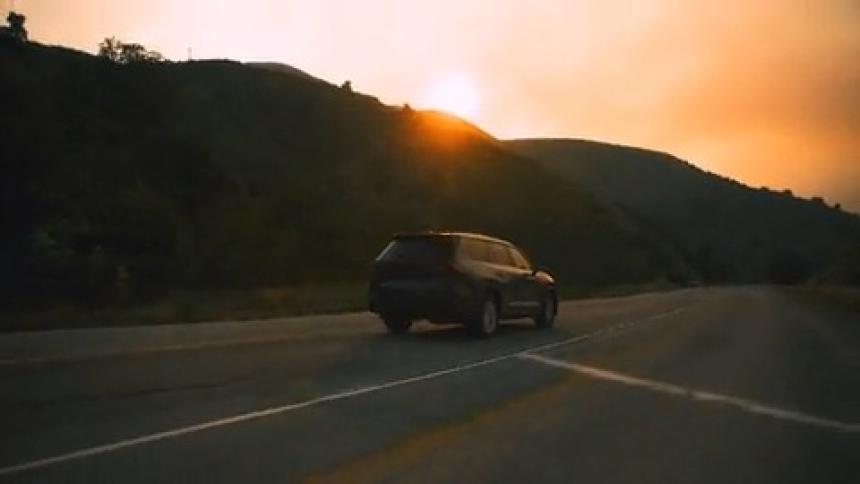 SUV driving through mountain road under smoky sky