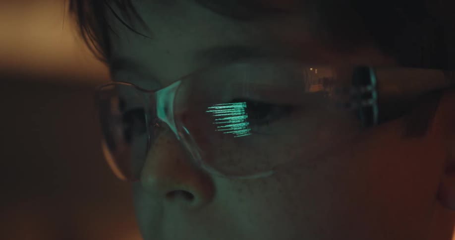 Portrait of a boy with glasses reflecting coding on a screen